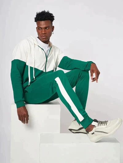 a man in a green and white hoodie sitting on a white cube